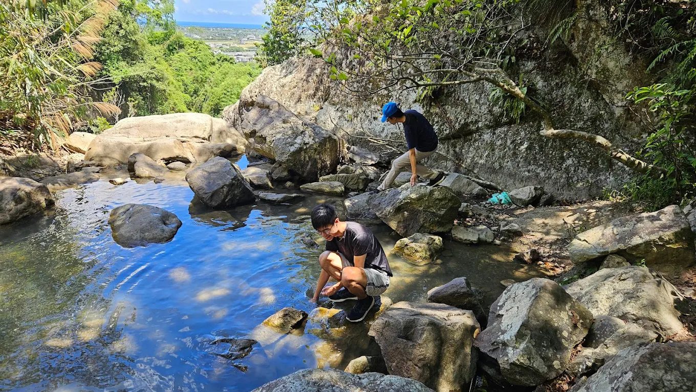五峰旗瀑布風景區岩石水池中玩水的遊客,周圍被青翠山林環繞