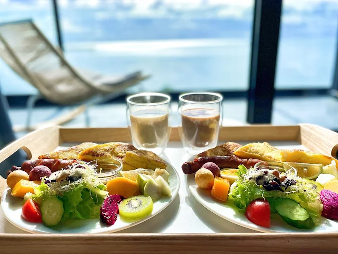 漫漫日出民宿的雙人早餐套餐擺在陽光照射的桌上，背景是太平洋海景
