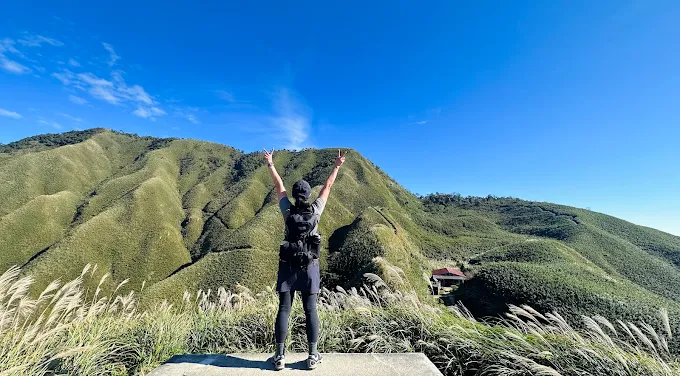 登山客在抹茶山頂舉手歡呼,遠望宜蘭聖母登山步道的翠綠山景與山莊