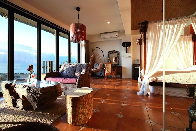 花蓮慢點海景民宿的峇里島風格房型，設有落地窗與海景陽台，搭配實木桌椅與吊燈，空間自然放鬆
