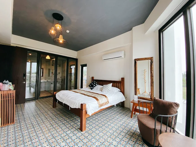 SunnyCorner B&B 四樓房型，擁有大片落地窗面向花蓮海景，搭配木質格柵天花與沉穩色調傢俱
