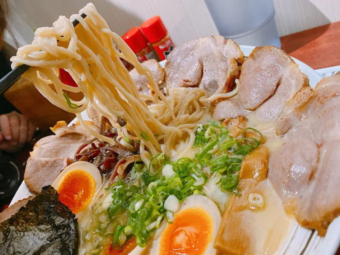 「台中佐原拉麵的豚骨拉麵，搭配濃郁湯頭、溏心蛋、炙燒叉燒與蔥花的拉麵特寫」
