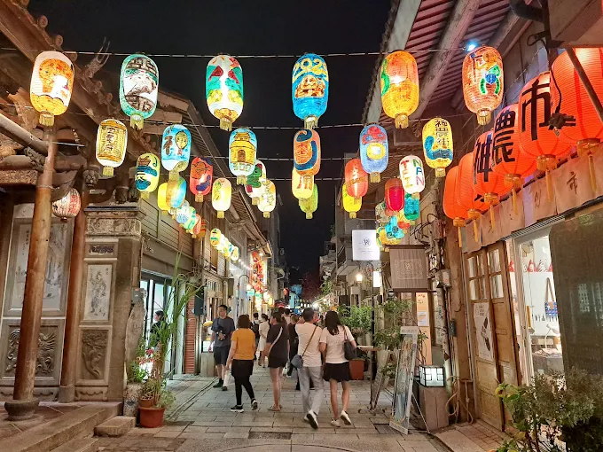 夜晚的台南神農街掛滿彩繪燈籠，遊客穿梭於古老街屋與文創店鋪之間，展現濃厚的歷史與藝術氛圍