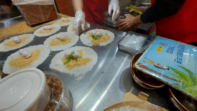 攤販現場製作花生捲冰淇淋，潤餅皮中加入花生糖粉、香菜與冰淇淋球
