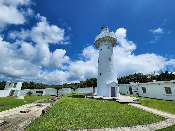 墾丁鵝鑾鼻燈塔白天景色，藍天白雲下的純白燈塔矗立於草地