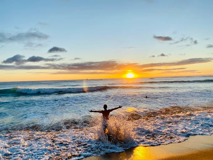墾丁白沙灣海灘夕陽景色，遊客在浪花中迎向金色夕陽