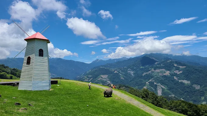 清境農場風車草原與遠方山巒，遊客在藍天下享受高山景色
