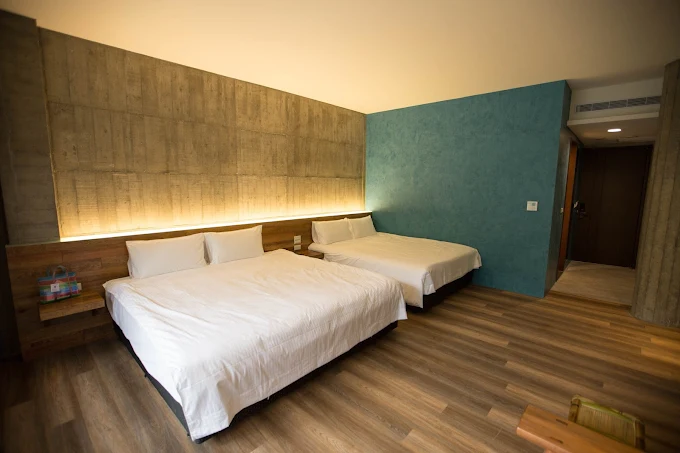 三富休閒農場紫森林四人房，兩張大床搭配木質地板與清水模設計，展現簡約舒適的住宿氛圍