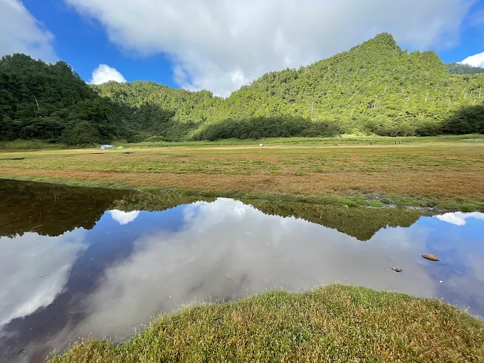 松蘿湖湖水映照藍天與白雲,周圍綠意環繞,展現靜謐氛圍的高山湖泊
