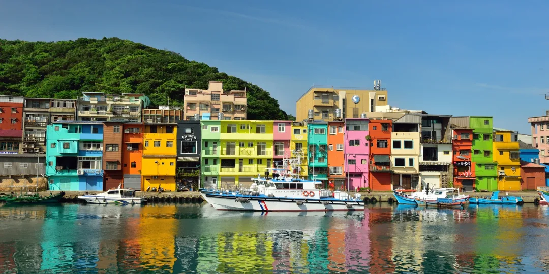 正濱漁港彩色街屋全景,藍天白雲下倒影清晰可見,展現出如威尼斯般的水都風情。