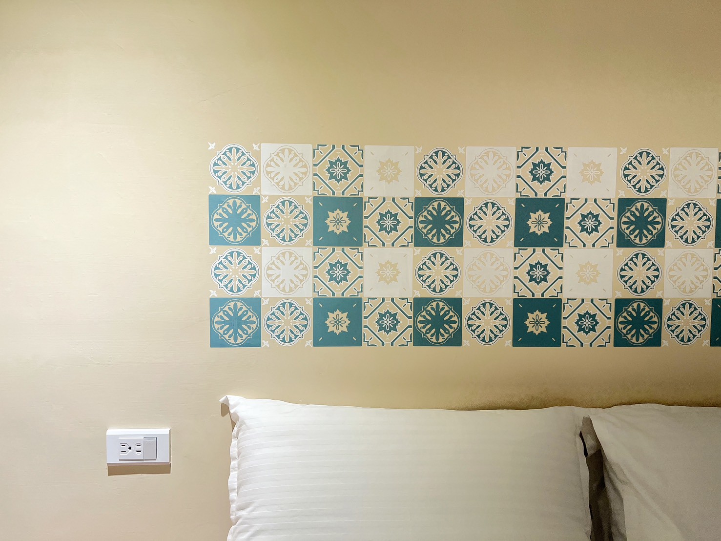 客房床頭牆面上的復古老磚紋印花設計，展現精緻的手作質感