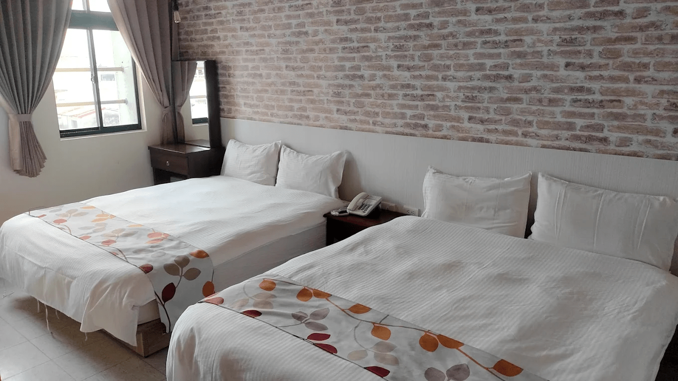 旅館內部房間實景，展示雙人床與基本的住宿設施配置