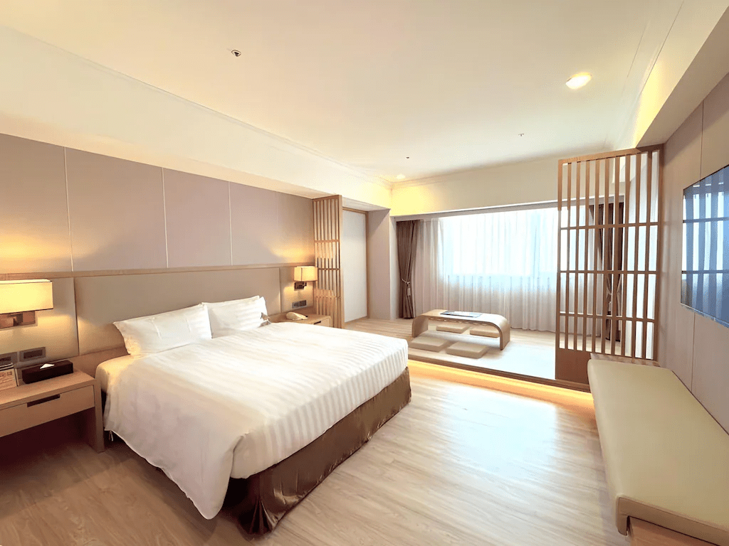 飯店客房內部一隅，床鋪整潔舒適，空間寬敞明亮，提供旅人一夜好眠