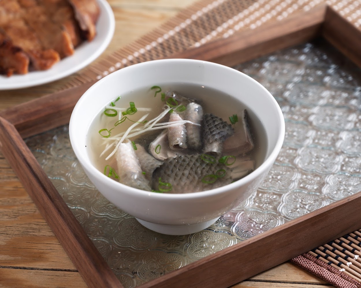 一碗清澈魚湯，裡面有魚肉、魚皮、蔥花與薑絲。