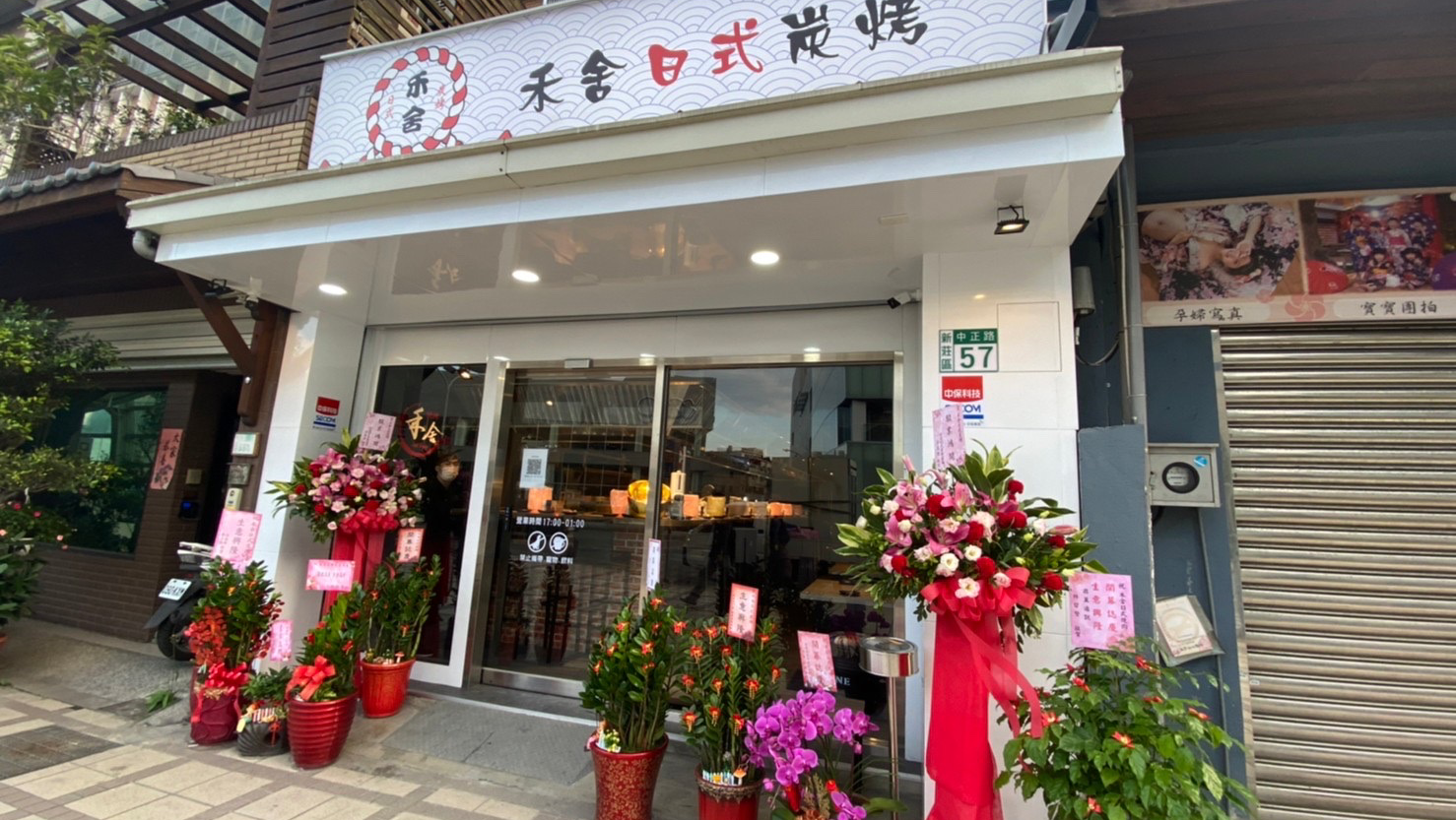 日式炭烤餐廳外觀，門口擺有開幕花籃與植栽