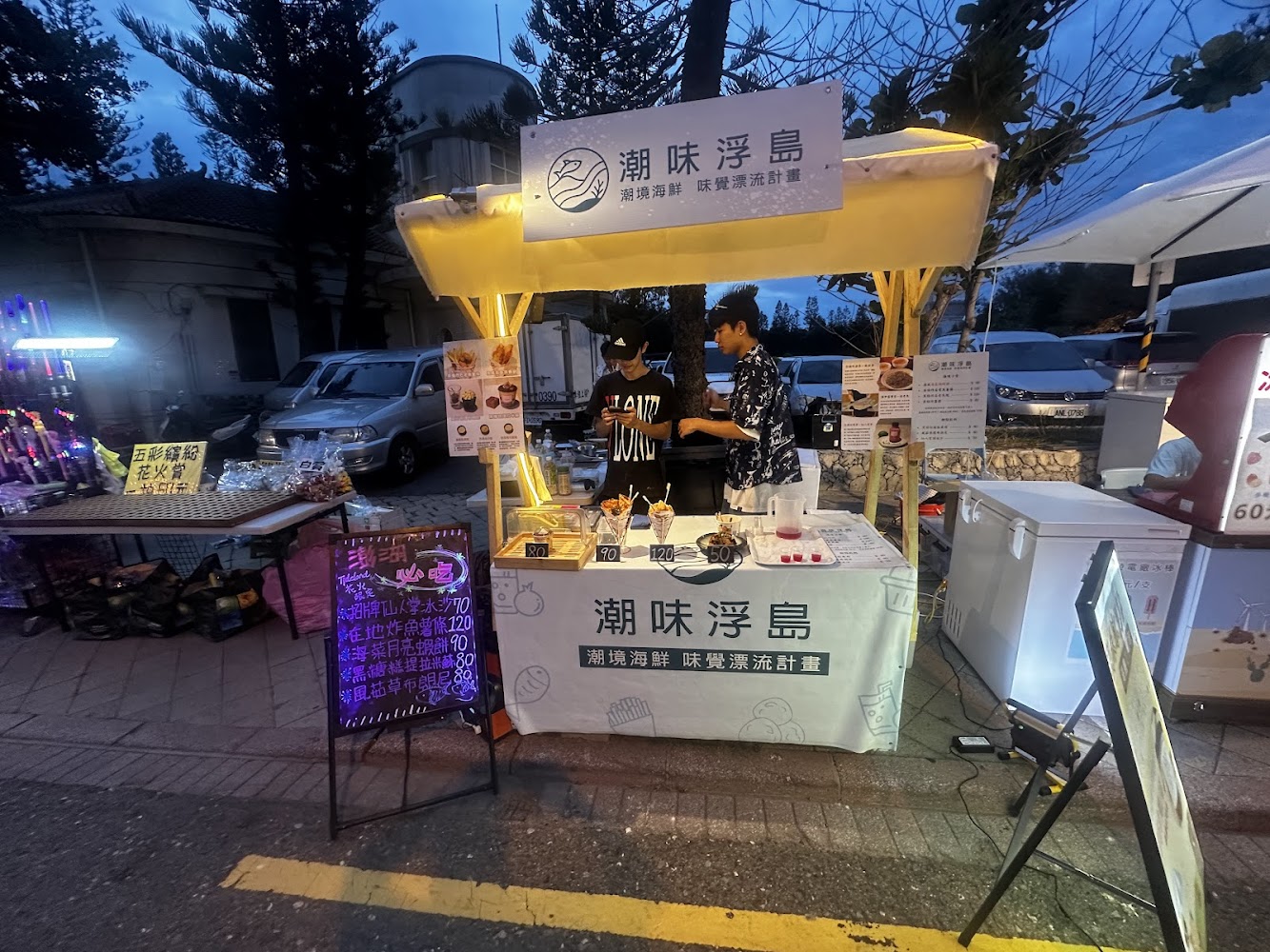 夜市海鮮攤位招牌醒目，攤販正在準備餐點。