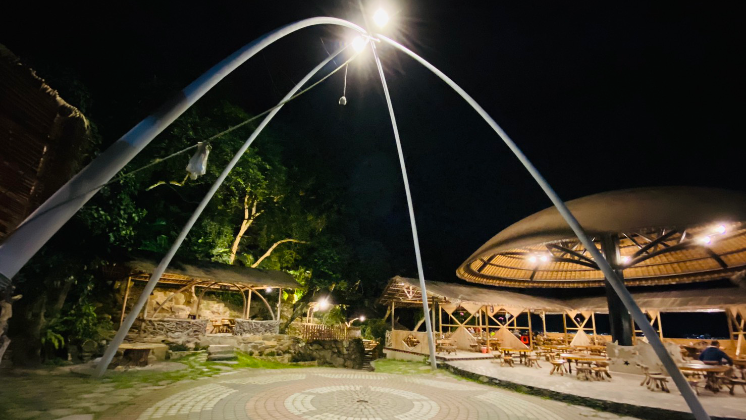 夜晚的戶外餐廳空間，有大圓拱型棚架與竹製桌椅區，氣氛寧靜