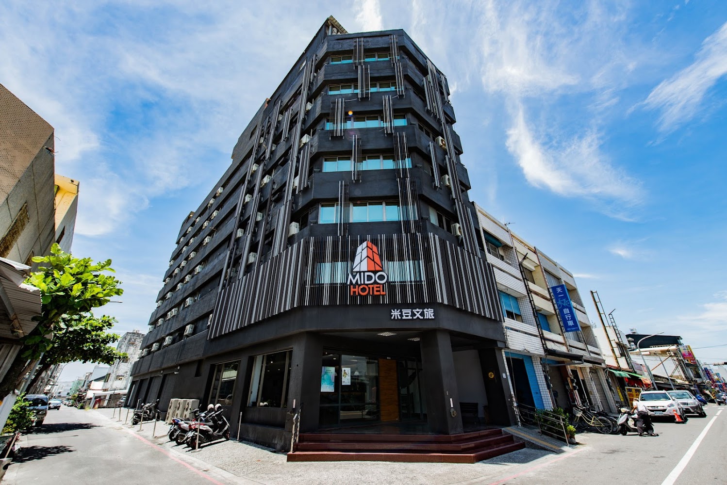 旅人驛站米豆文旅街角建築外觀，位於市區街道。