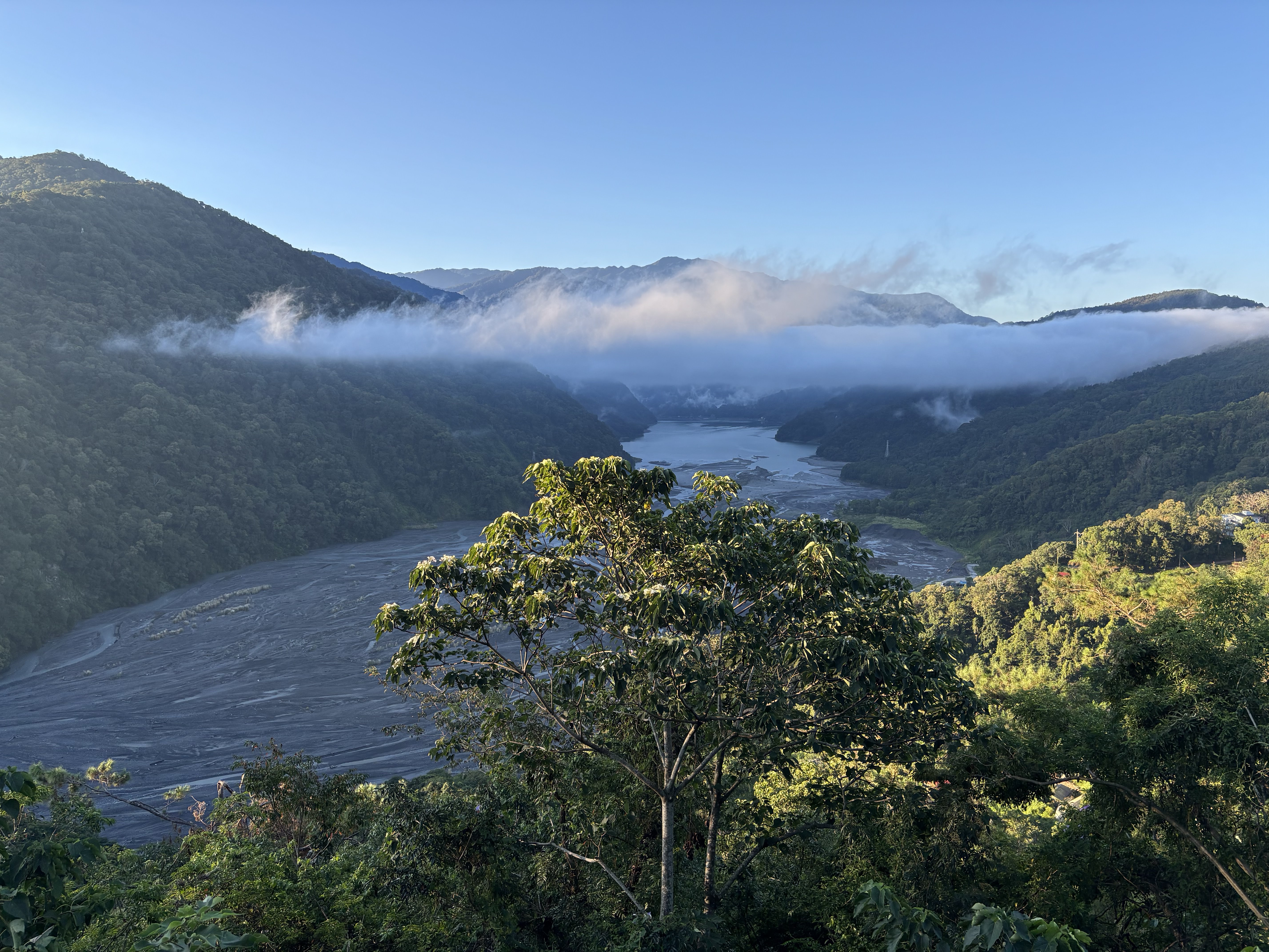 青山環繞的河谷風景，雲霧飄在山腰間