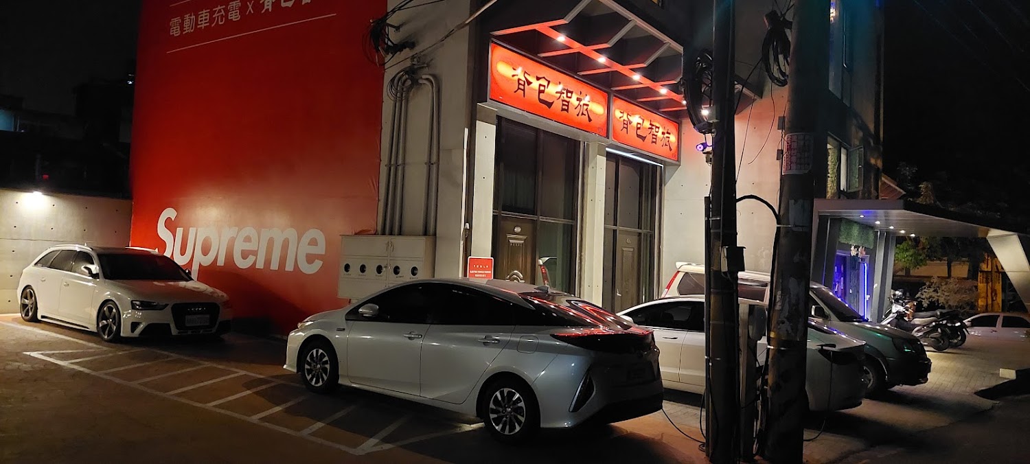 夜間建築外觀，門前停有汽車與機車