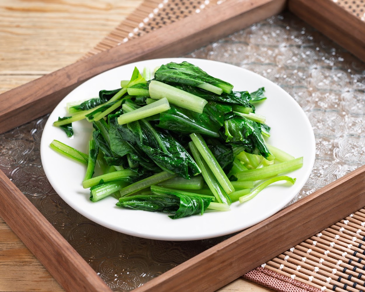 白色圓盤盛裝的炒青菜，葉色翠綠新鮮。