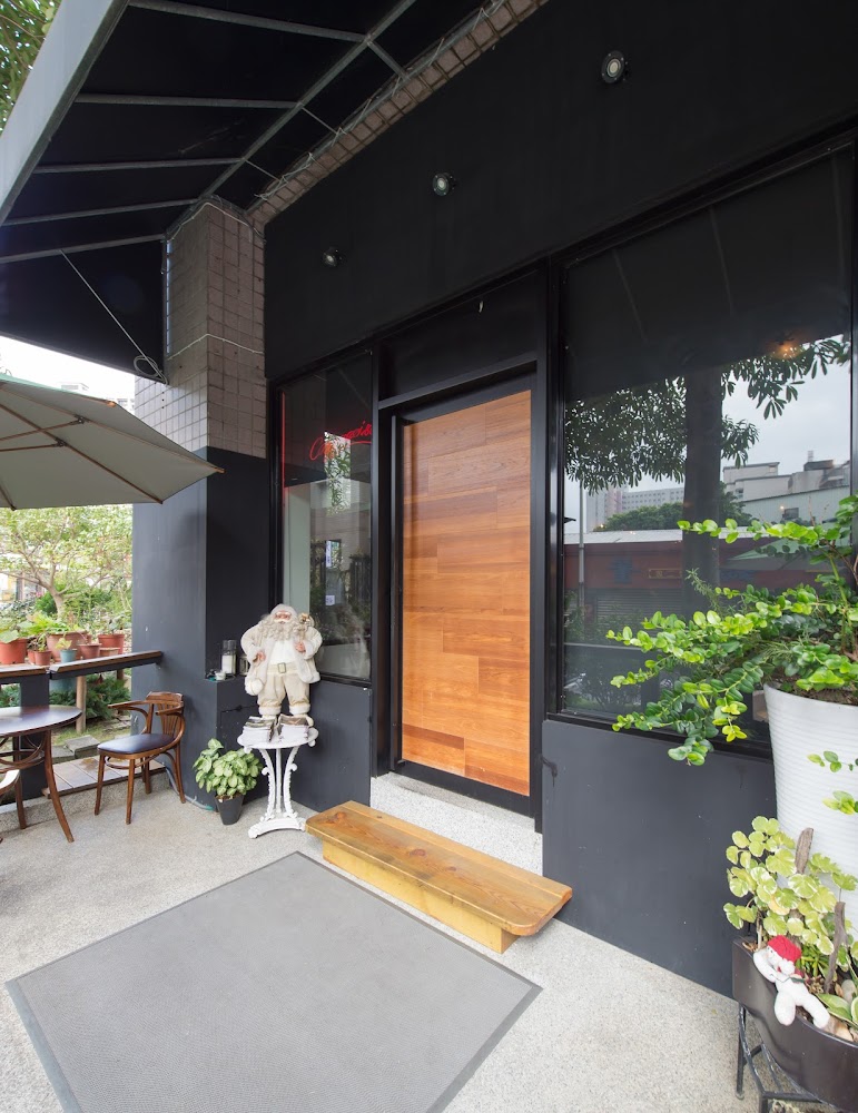 艾莉斯餐酒館門口，有木門、迎賓地墊、花草盆栽、聖誕老人裝飾以及室外座位區