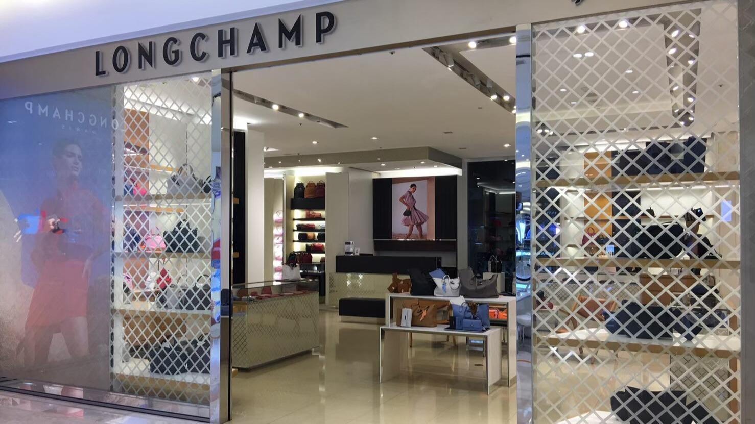 Longchamp 台中港路店專櫃展示架上陳列多款包袋，環境明亮高級
