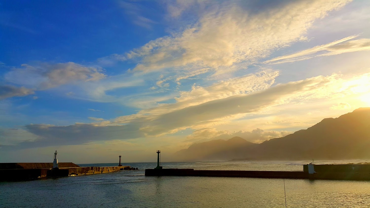 成功漁港夕陽景色，天空雲層豐富遠方有山海景觀