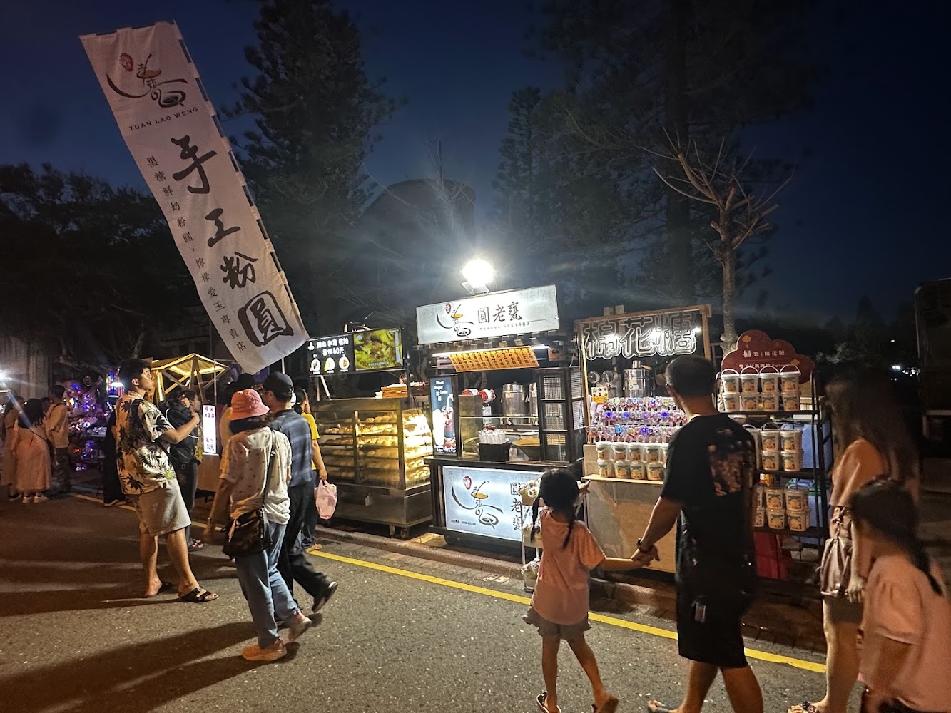 夜市中多個攤位販售食物與商品，人潮熱鬧。