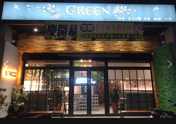 這是一家名為GREEN的餐廳，外觀以玻璃和木質裝潢為主，門口有慶開幕的橫幅。店面明亮，外觀設計現代且有綠意裝飾，給人舒適的感覺。