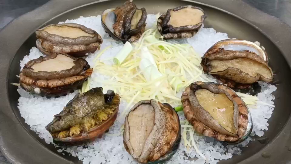 鮑魚擺放在碎冰上，中央有薑絲與蔥段