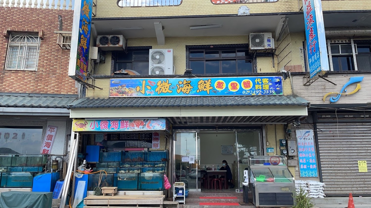 小微海鮮餐廳外觀，門口有水族箱與醒目招牌，主打萬里蟹與海產料理