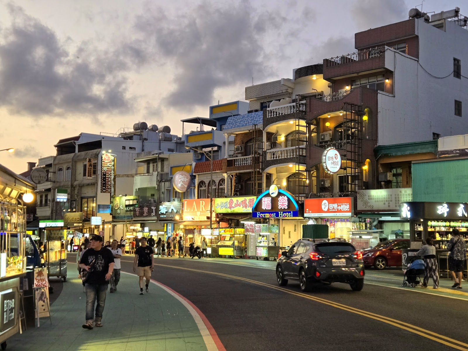 墾丁大街夜晚街景，霓虹燈牌閃爍，人群熙攘