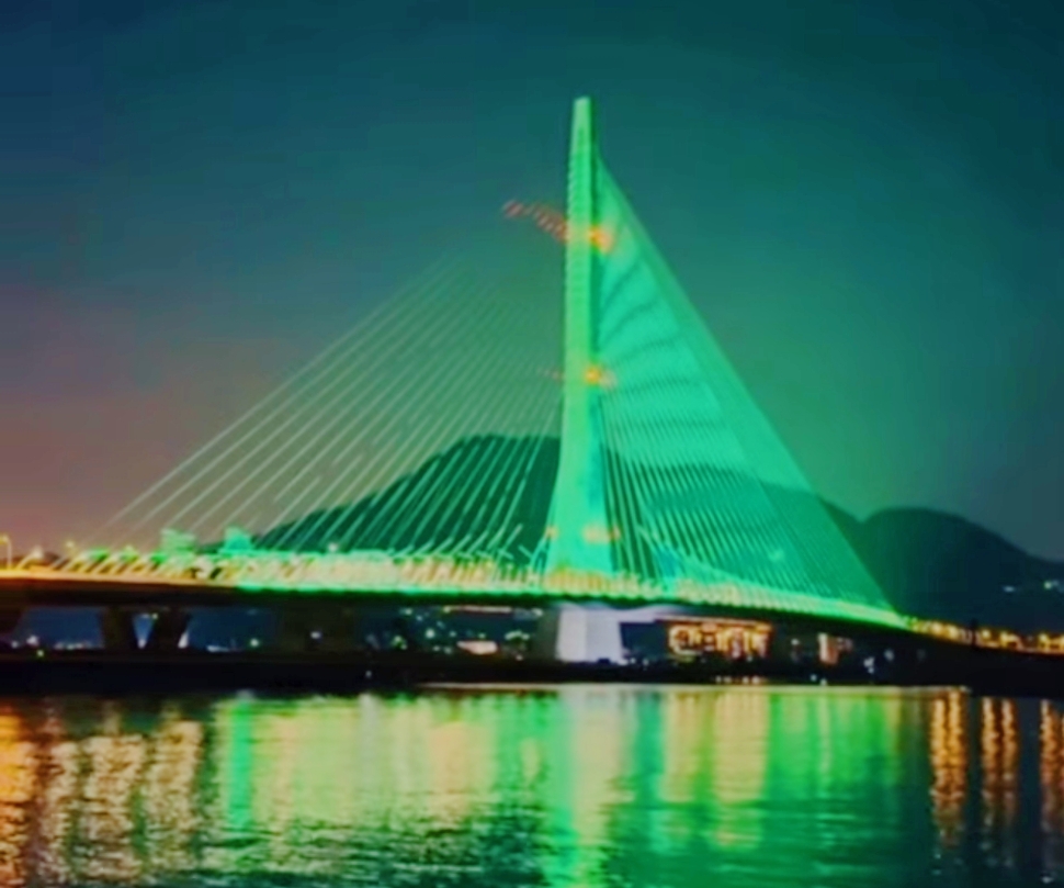 淡水夜景，斜拉橋亮起綠色燈光，燈影倒映在淡水河面