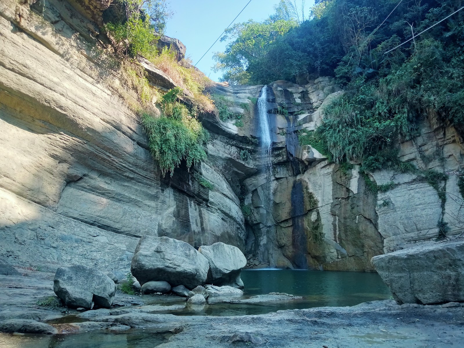 屯阿巴娜步道瀑布，溪水傾瀉於砂岩水潭，大型岩石環繞