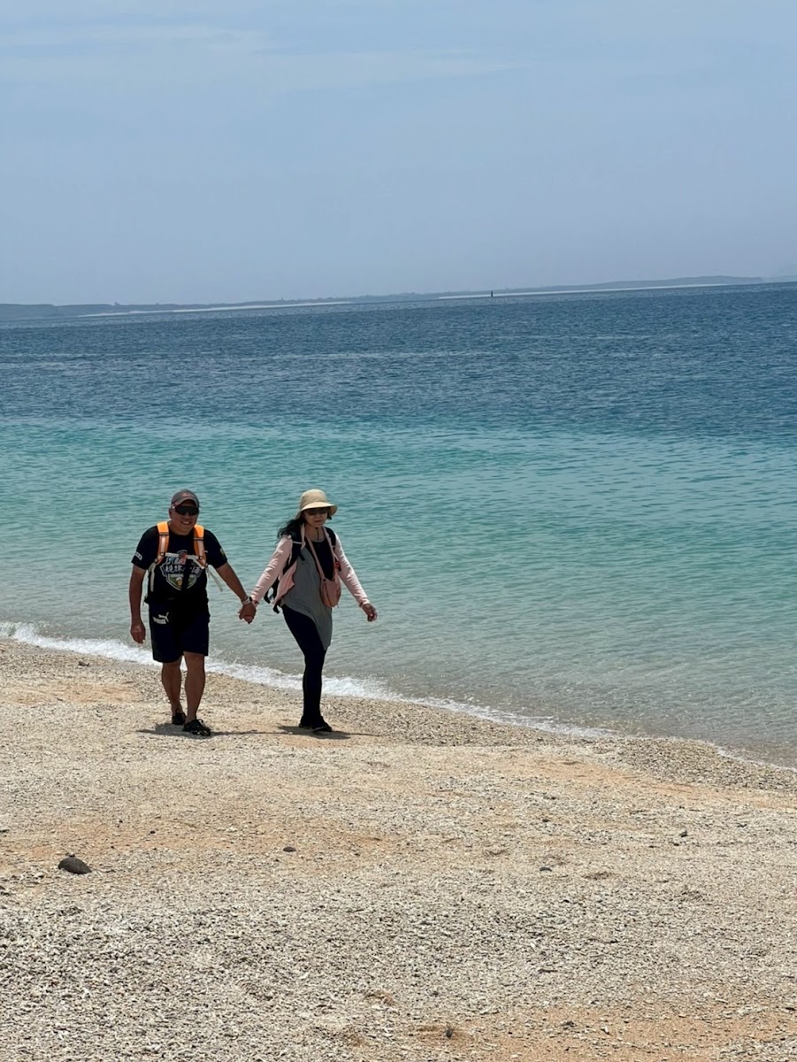澎湖吉貝島情侶在白沙灘海邊牽手散步