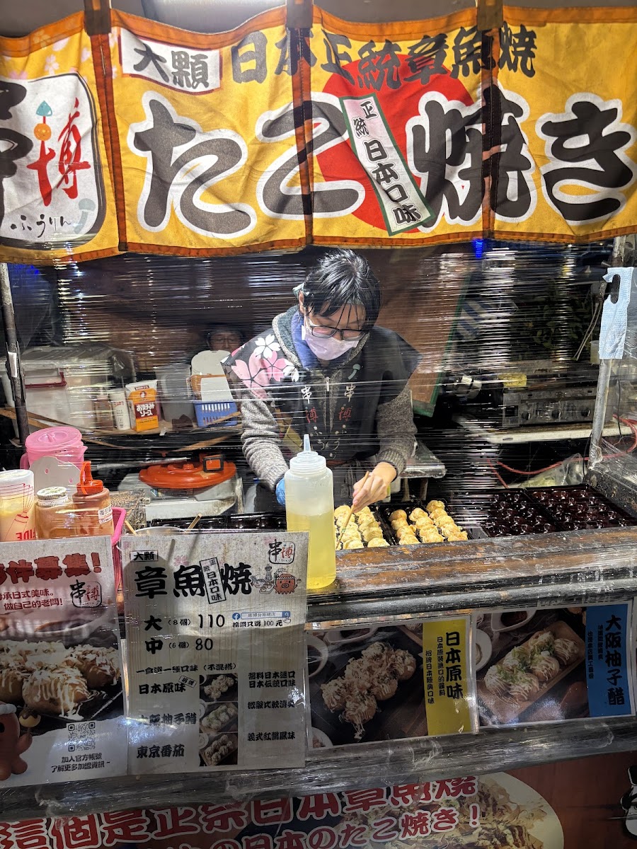 台南花園夜市章魚燒攤位，攤主正在翻面煎烤章魚燒，現場人氣旺