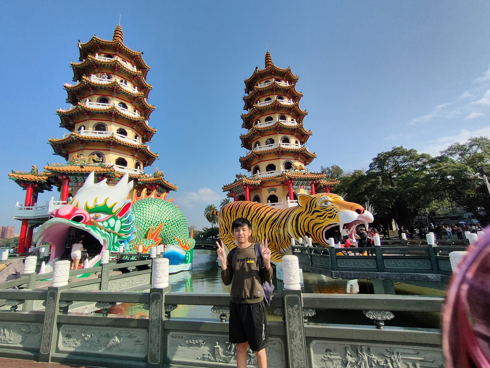 龍虎塔近景，龍虎雕像入口清晰，少年遊客站在橋上比YA