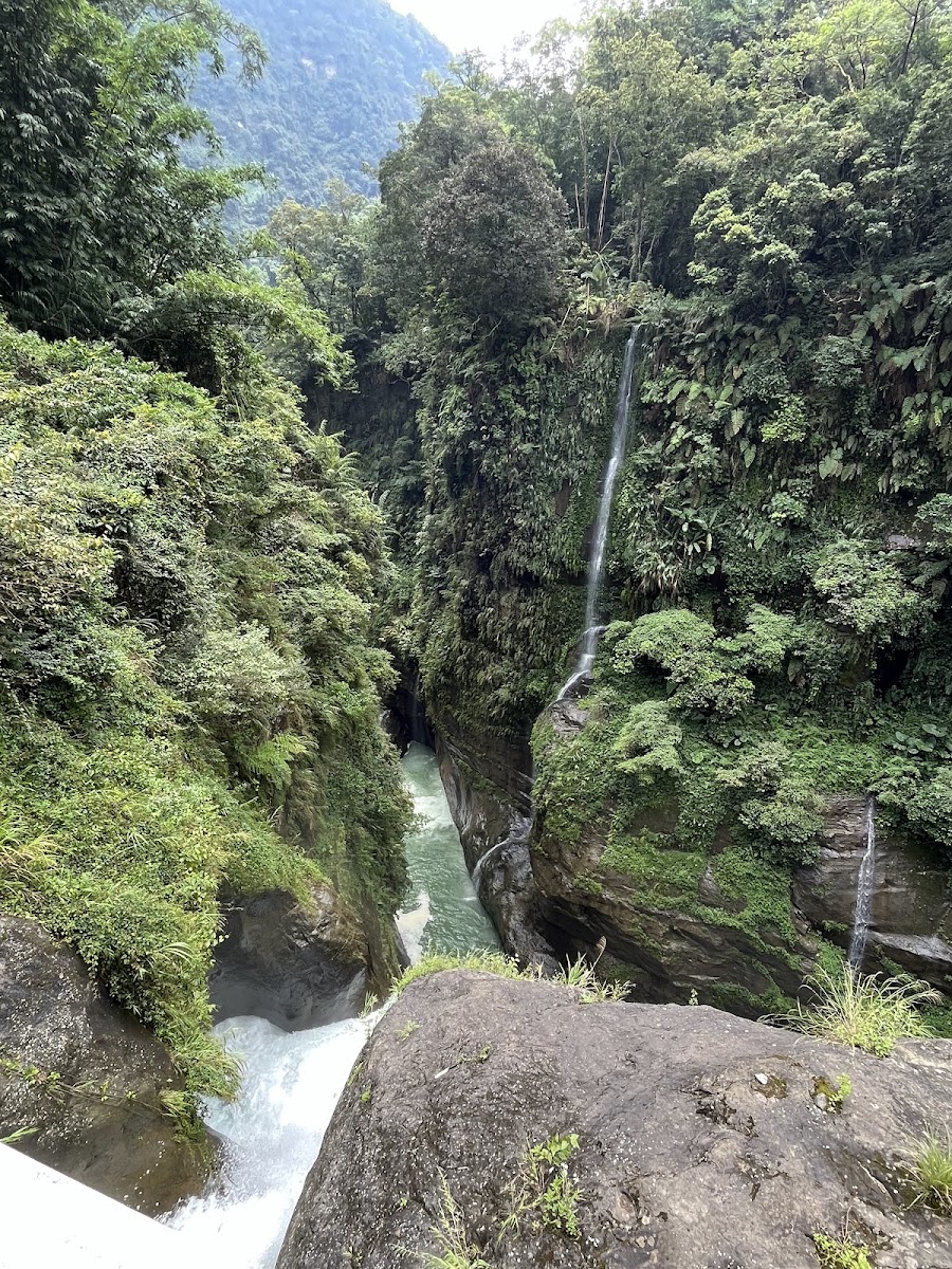 竹山天梯景區山谷瀑布俯瞰,瀑布從綠色山崖流下,河流穿過巨石