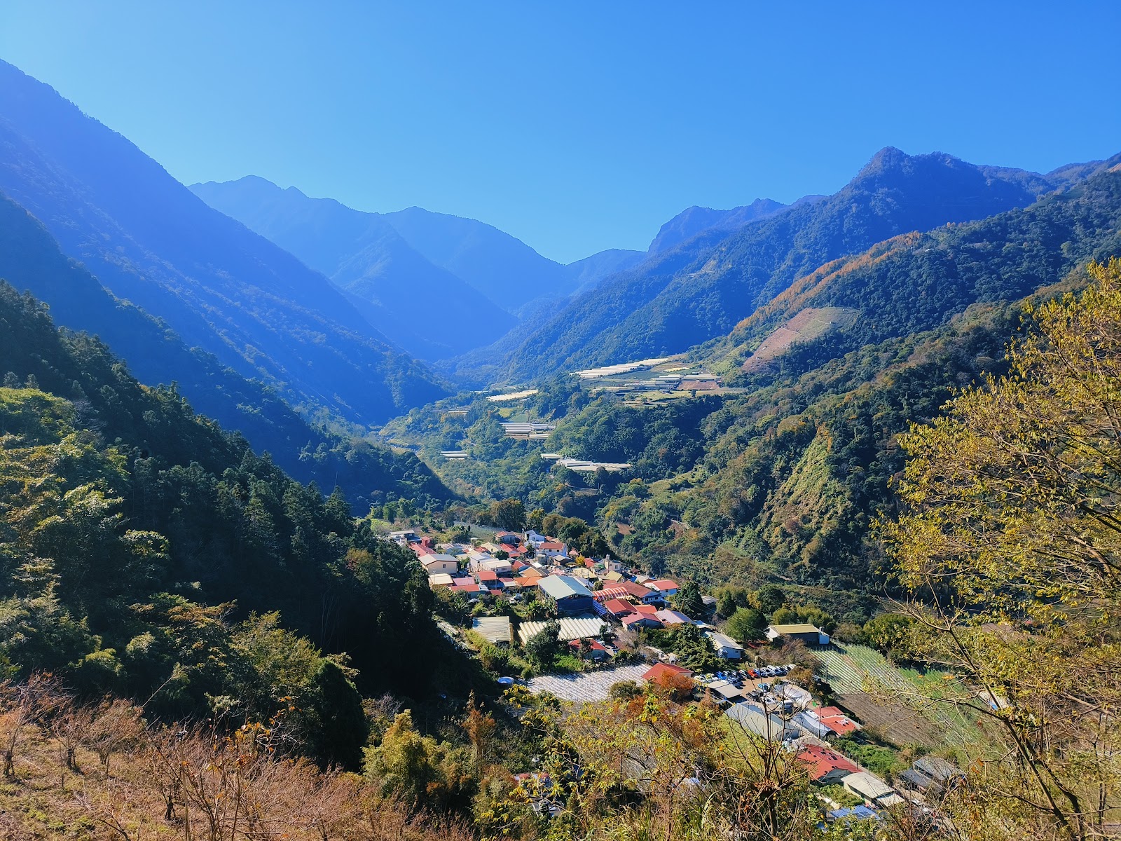 從制高點俯瞰東埔部落，紅屋頂建築群散落在山腰，四面群山環抱藍天