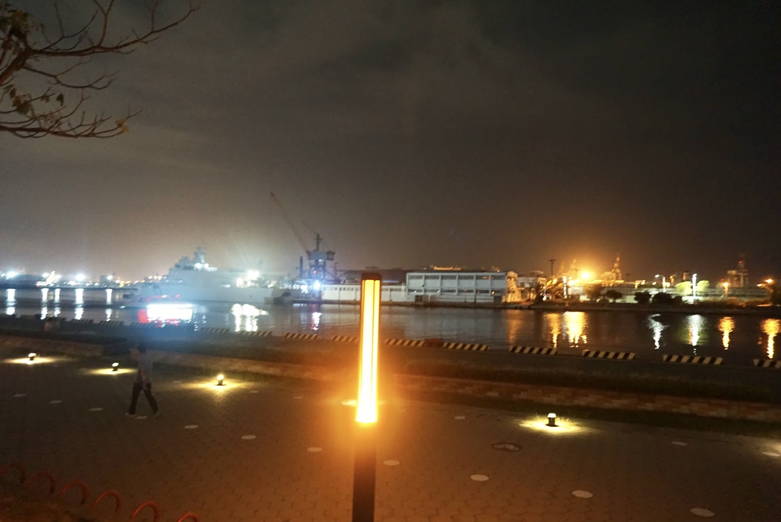 駁二港邊夜景，燈柱橘光，對岸工業設施燈火倒影