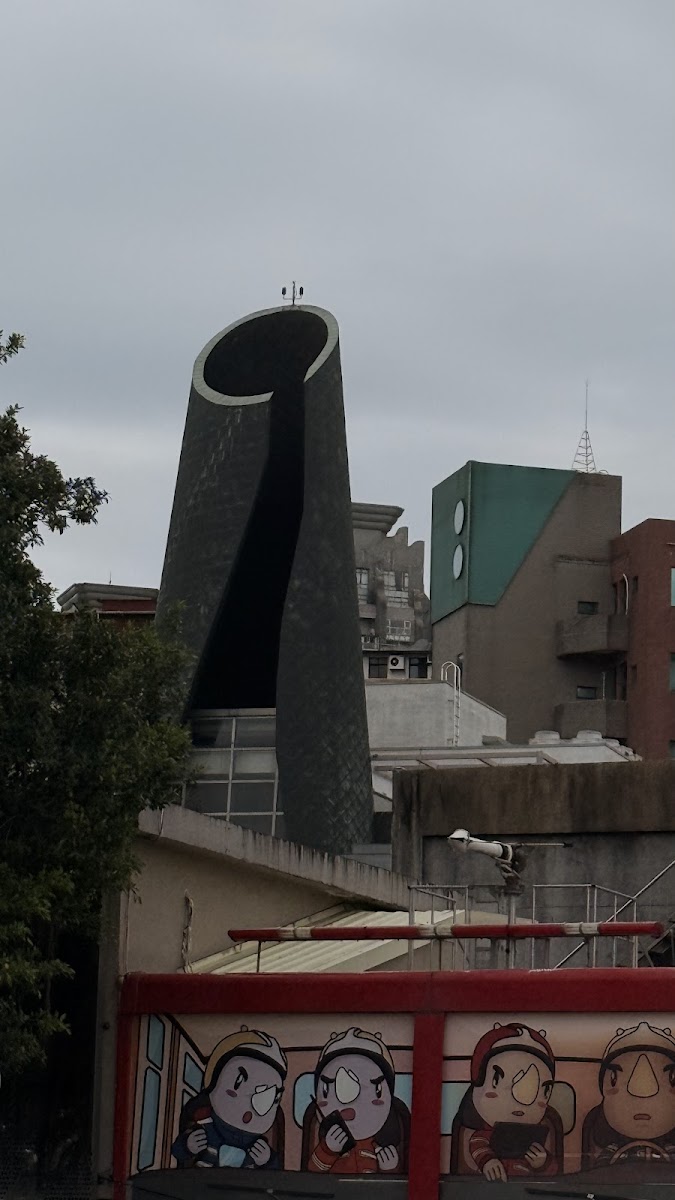 淡水老街附近特殊造型建築，頂部有圓弧開口，前方有卡通人物彩繪藝術
