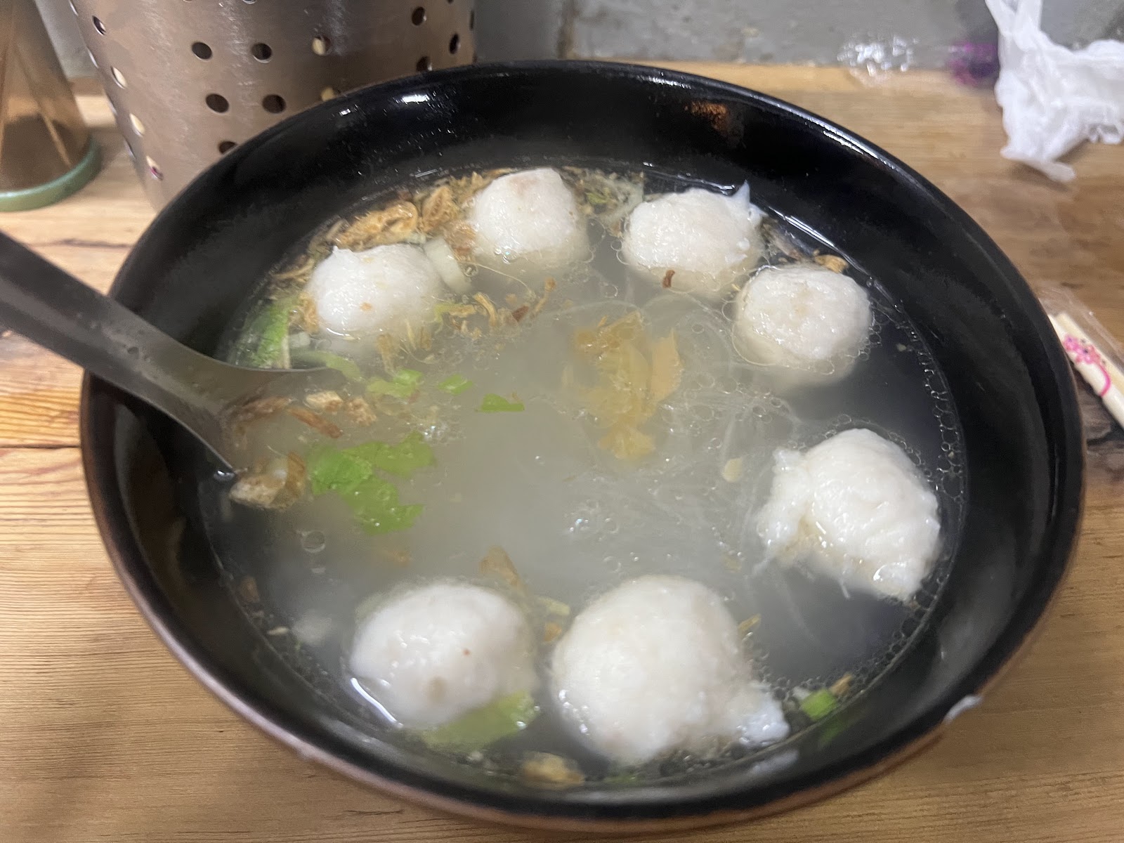 黑碗盛裝的九份魚丸湯，六顆大魚丸漂浮清湯中，蔥花與柴魚片點綴
