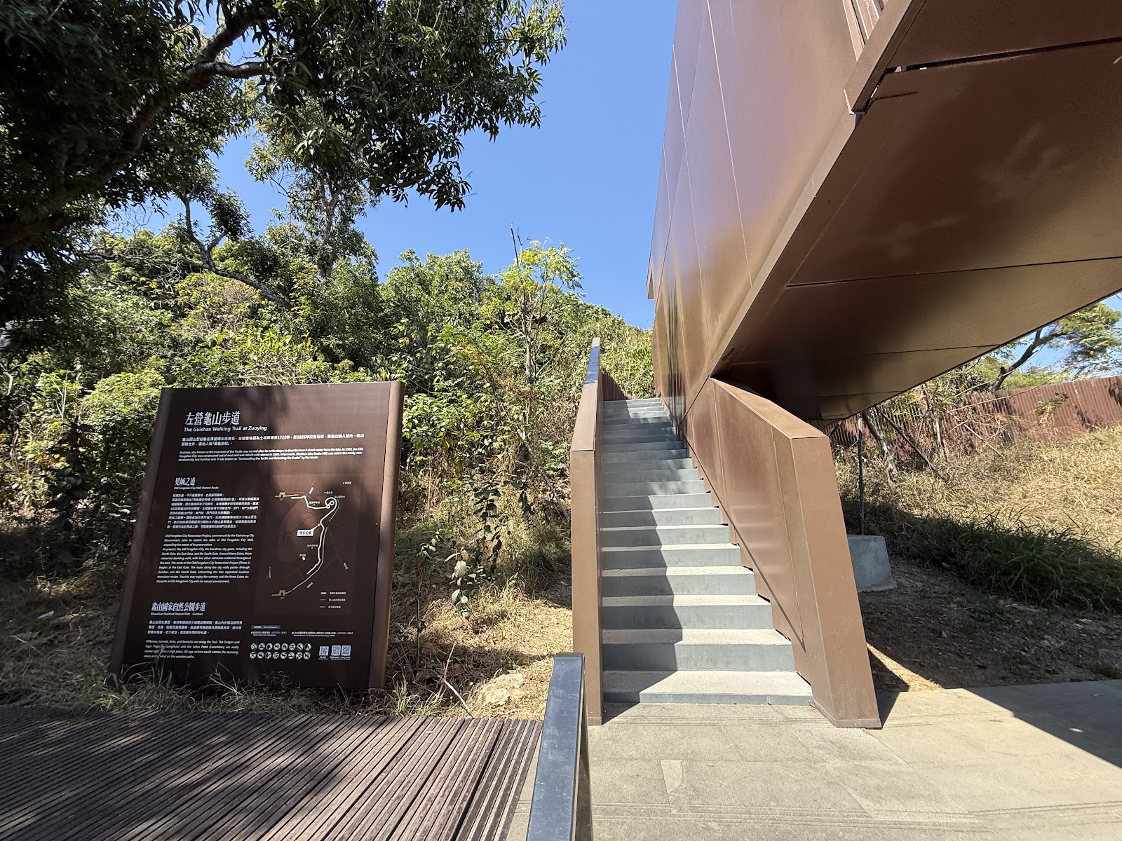 左營龜山步道入口指示牌，階梯整潔，現代棕色建築，藍天綠樹