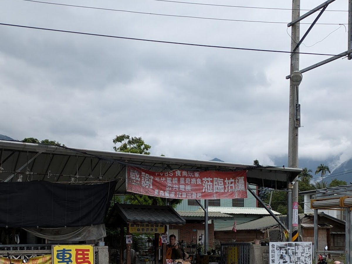 慶修院馬告香腸攤位從馬路對面拍攝的全景遠照，黃色招牌紅色橫幅