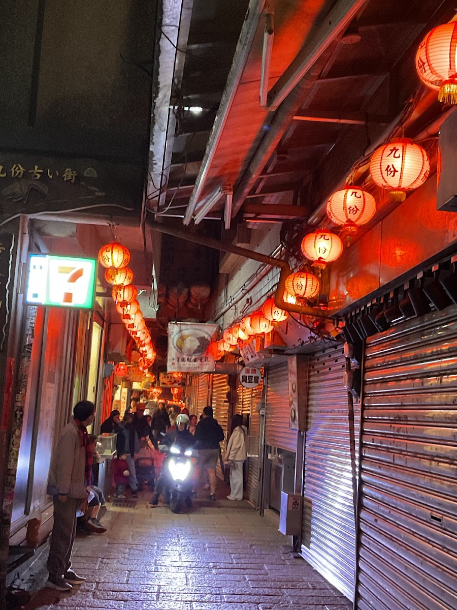 九份老街夜晚狹巷兩排紅燈籠點亮機車穿越7-11招牌