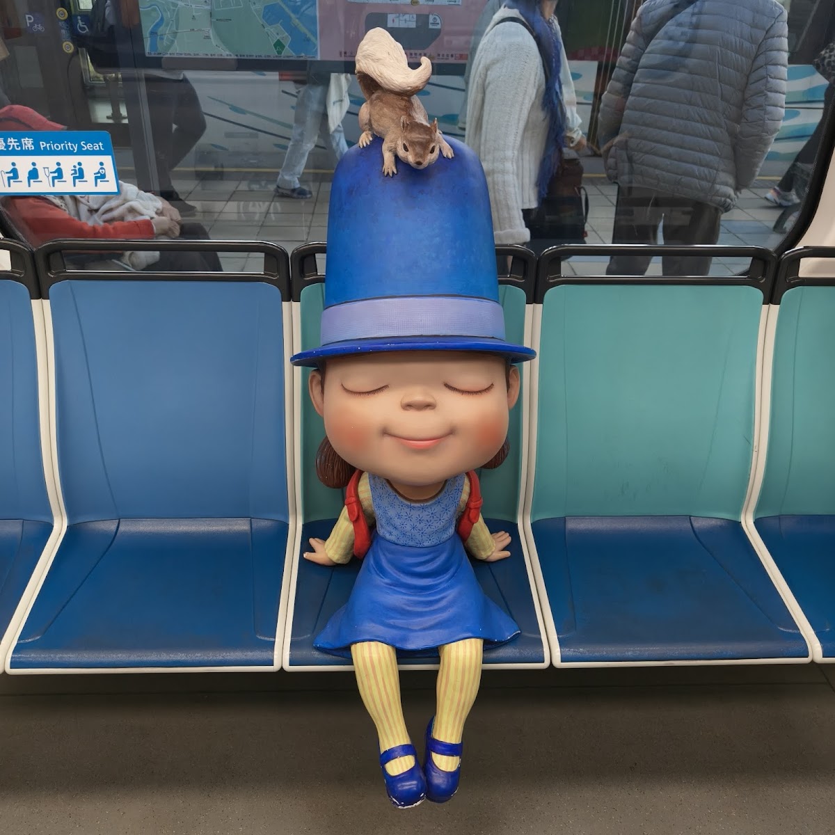 淡水輕軌車廂內藍色洋裝女孩公仔坐在藍色座椅上,表情可愛
