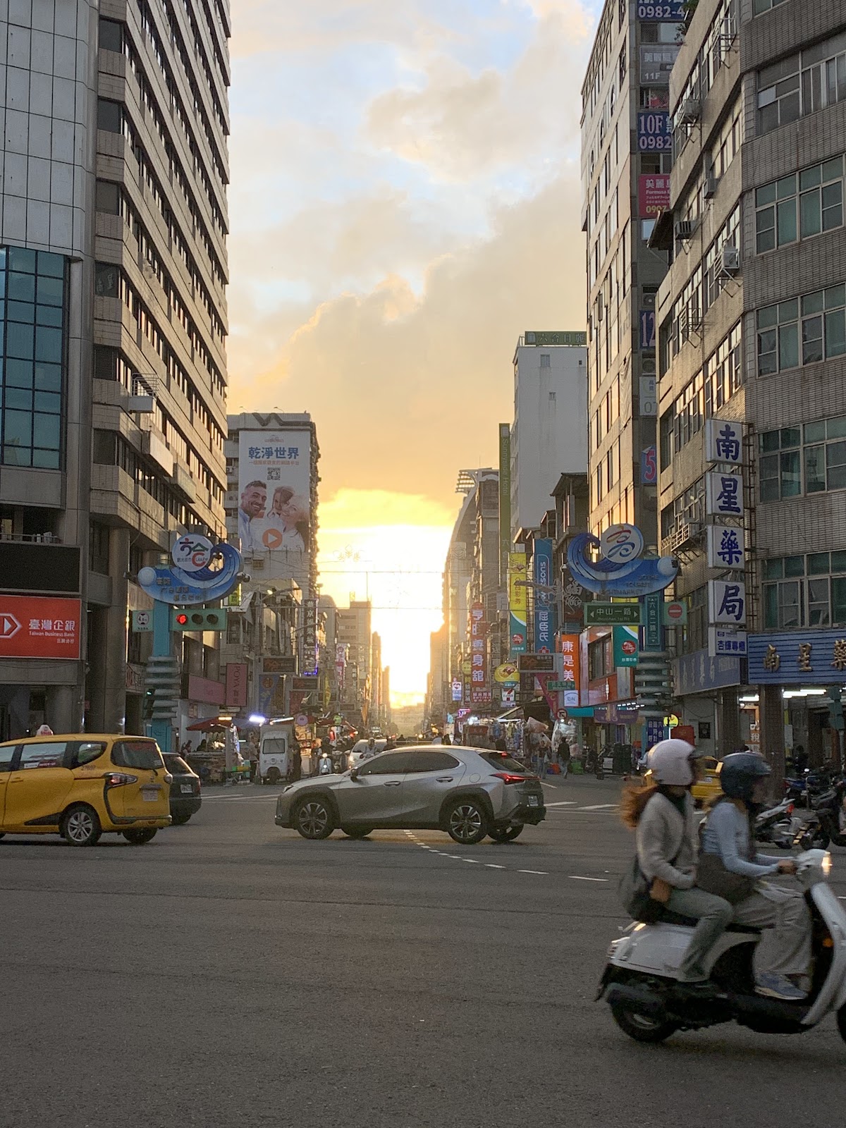 六合路黃昏路口,一對騎士騎機車穿越路口,城市感十足