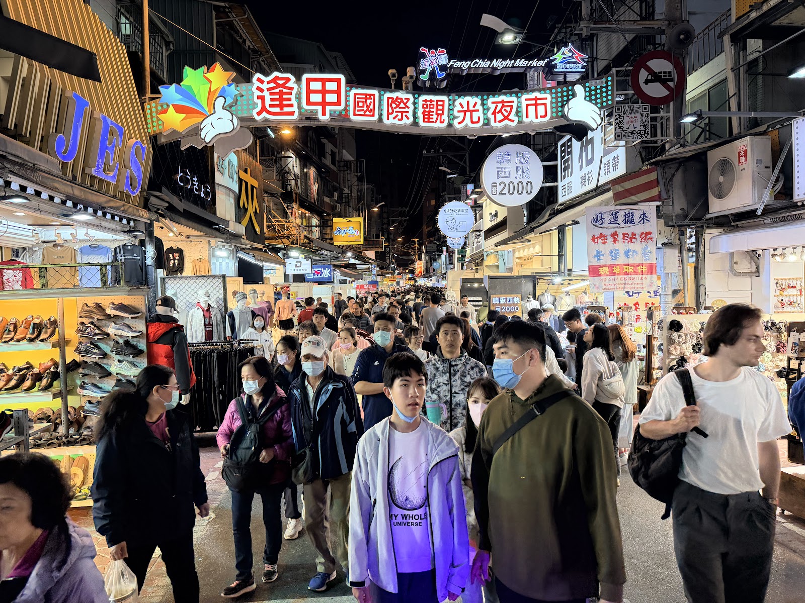 逢甲夜市主入口牌樓夜景，人潮熙攘，霓虹燈光閃爍