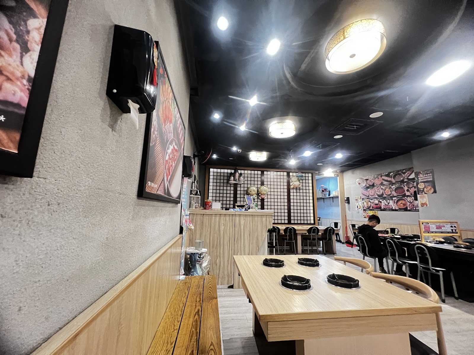 誠石火鍋岡山店室內空間寬敞，黑色天花板搭配現代燈光，木質桌椅整齊排列